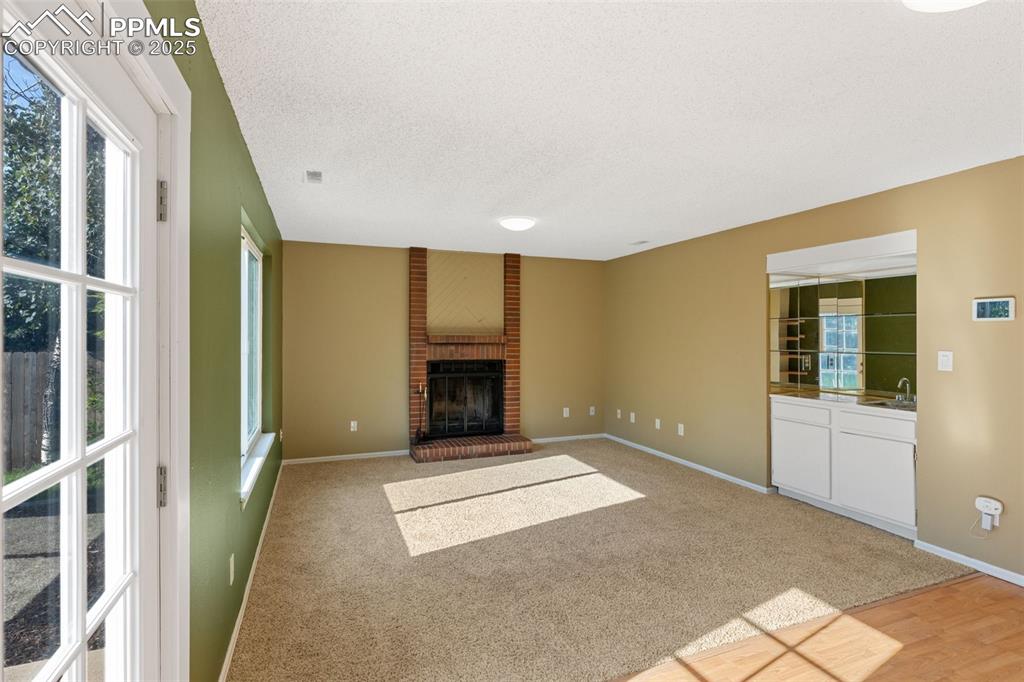 Image 10 of 33: Unfurnished living room featuring a brick fireplace, light colored carpet,