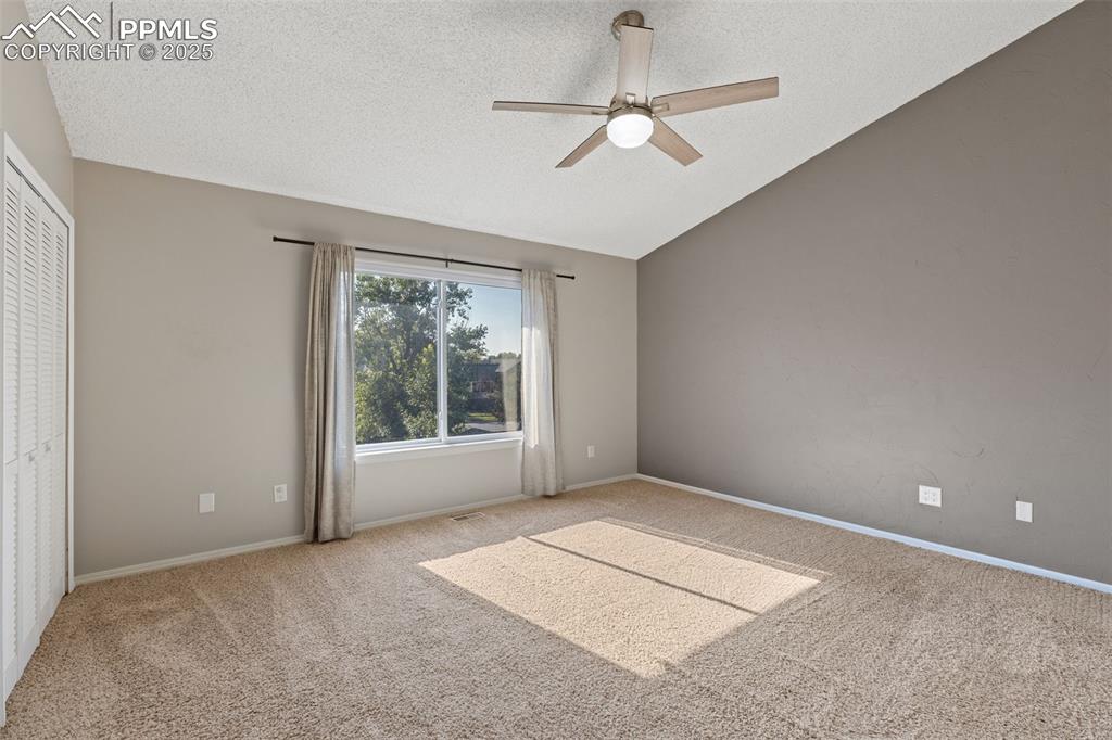 Image 13 of 33: Carpeted empty room with a textured ceiling, lofted ceiling, and a ceiling