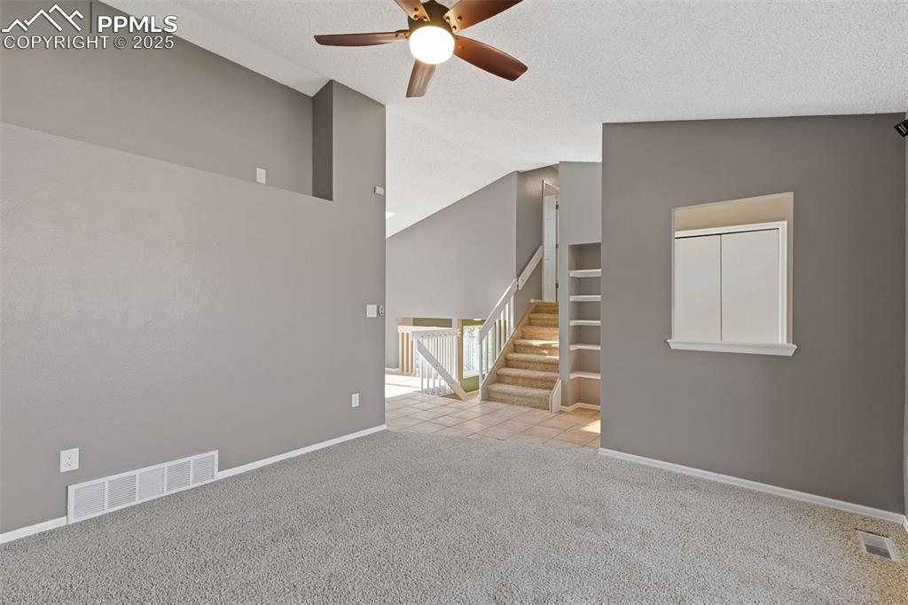 Image 4 of 33: Empty room featuring carpet floors, ceiling fan, high vaulted ceiling, and