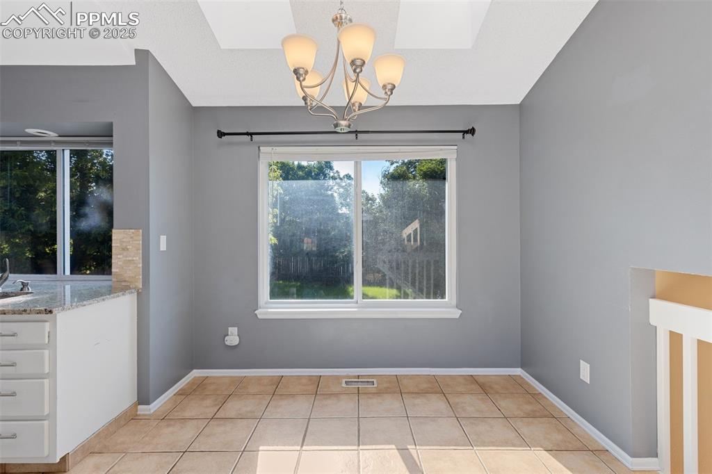 Image 6 of 33: Unfurnished dining area with light tile patterned floors, a chandelier, and