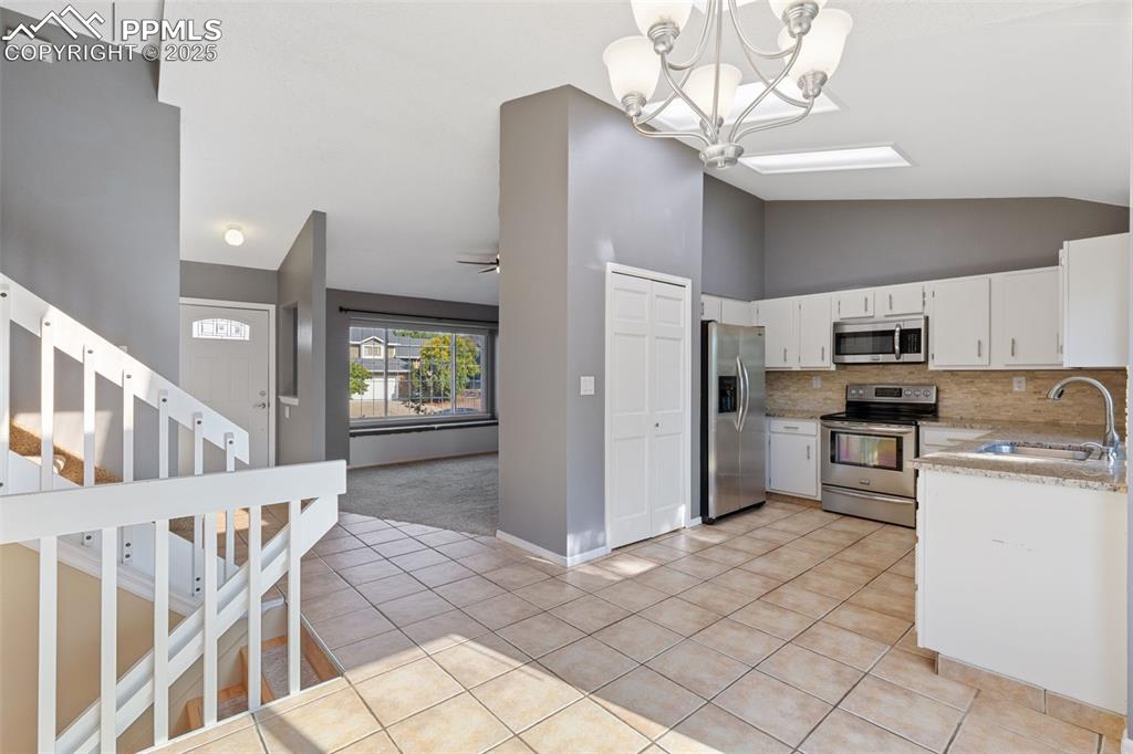 Image 7 of 33: Kitchen featuring stainless steel appliances, decorative backsplash, light