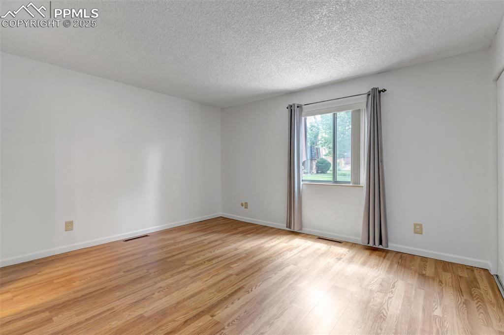 Image 19 of 37: Empty room with a textured ceiling and light wood-type flooring