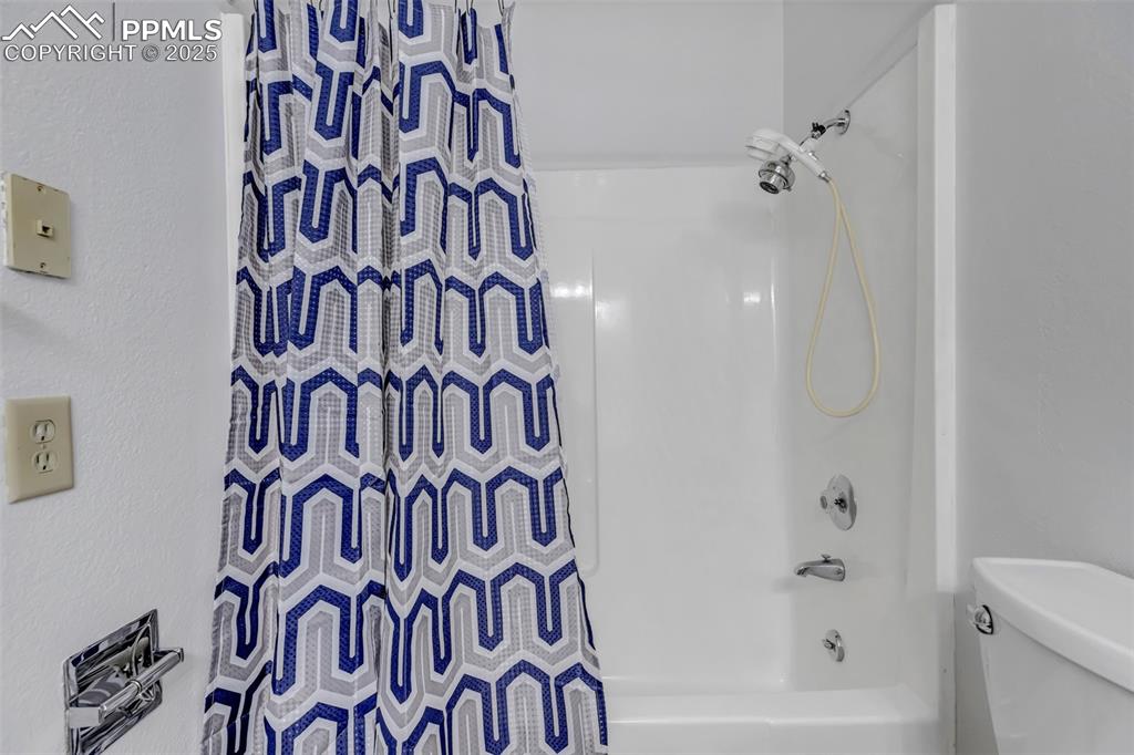 Image 23 of 37: Full bath with shower / tub combo with curtain and a textured wall