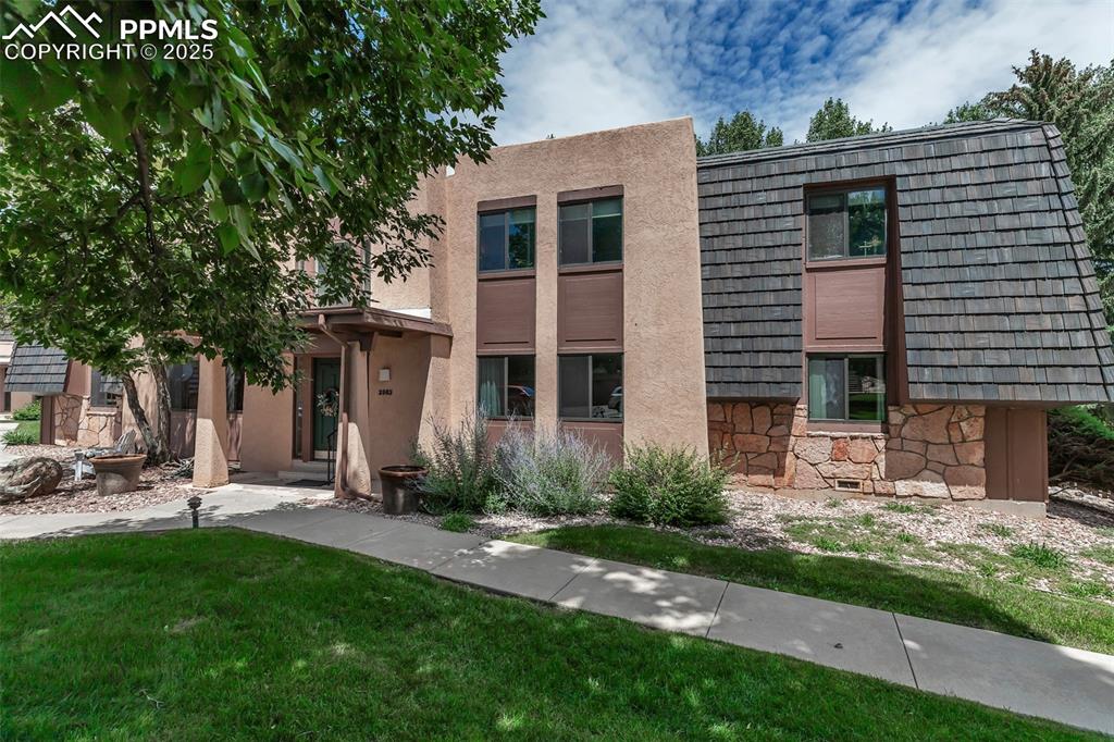 Image 32 of 37: View of front of home featuring stone siding, stucco siding, and a front ya