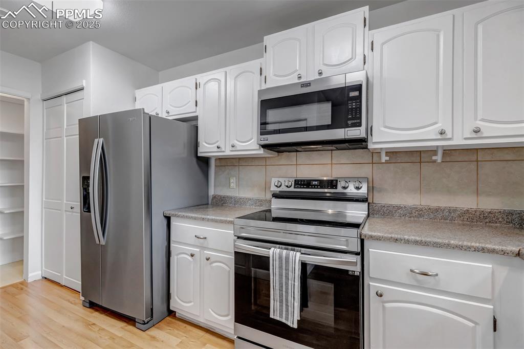Image 4 of 37: Kitchen featuring stainless steel appliances, backsplash, white cabinetry,