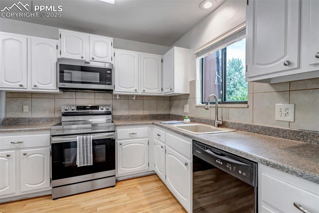 Image 9 of 37: Kitchen with SS appliances with stainless steel finishes, light wood-style