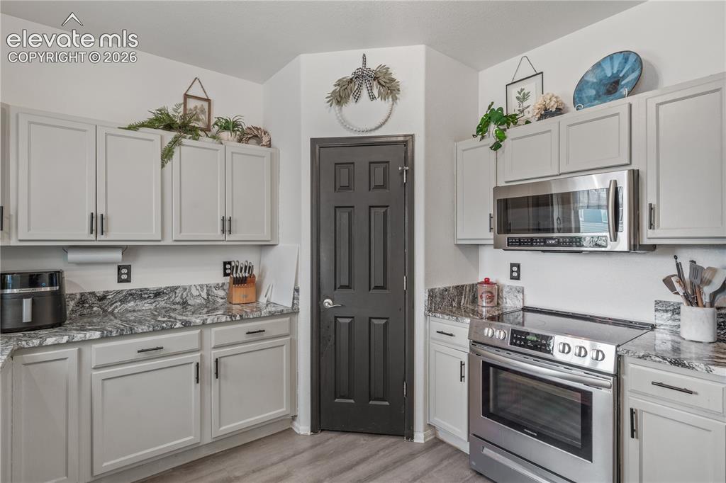 Image 11 of 41: Kitchen featuring light gray cabinetry with black hardware, mottled gray co