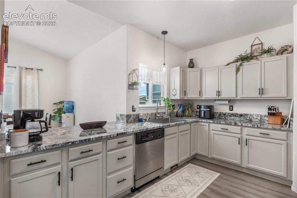 Image 12 of 41: Contemporary kitchen featuring light gray cabinetry, dark pulls, and patter