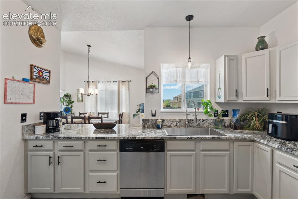 Image 13 of 41: Kitchen featuring light-toned cabinetry, dark hardware, and speckled counte