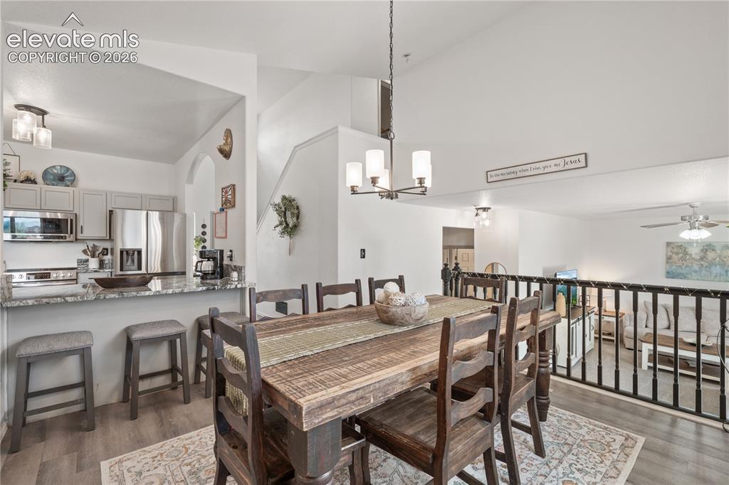 Image 15 of 41: Dining area featuring vaulted ceilings, a contemporary chandelier, and wood