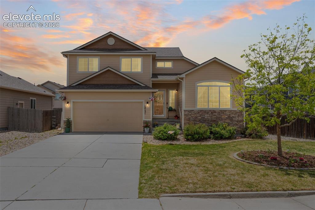 Image 2 of 41: Two-story residence featuring a two-car garage, stone facade accents, and a