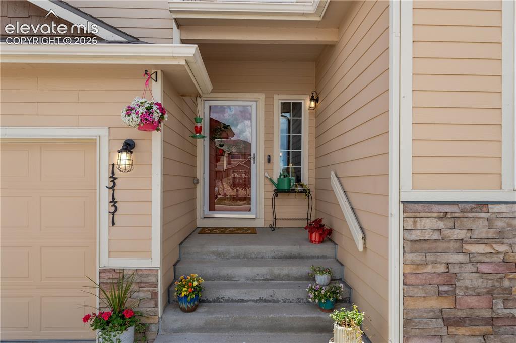 Image 5 of 41: Residential exterior featuring a two-car garage, partial stone facade, arch