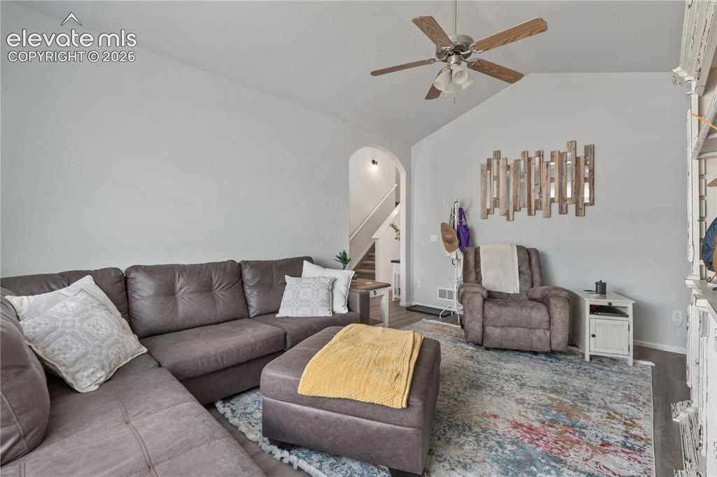 Image 9 of 41: Vaulted ceiling living area featuring a ceiling fan, a large picture window