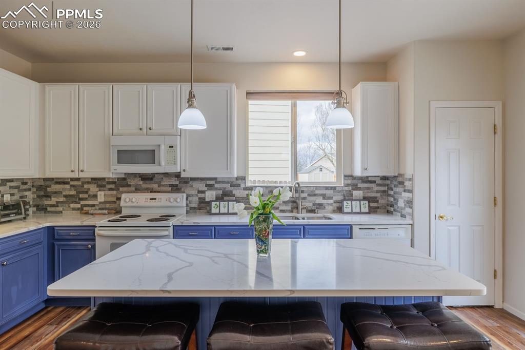 Image 13 of 36: Custom pendants over island and upgraded lighting throughout the home