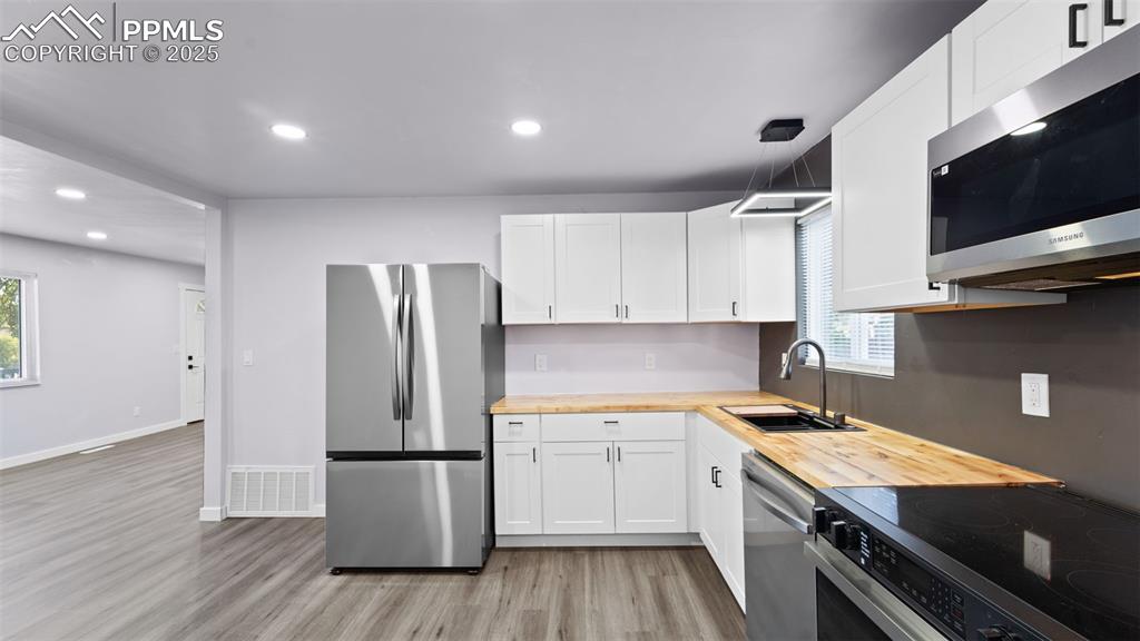 Image 12 of 28: Kitchen featuring stainless steel appliances, wood counters, light wood fin