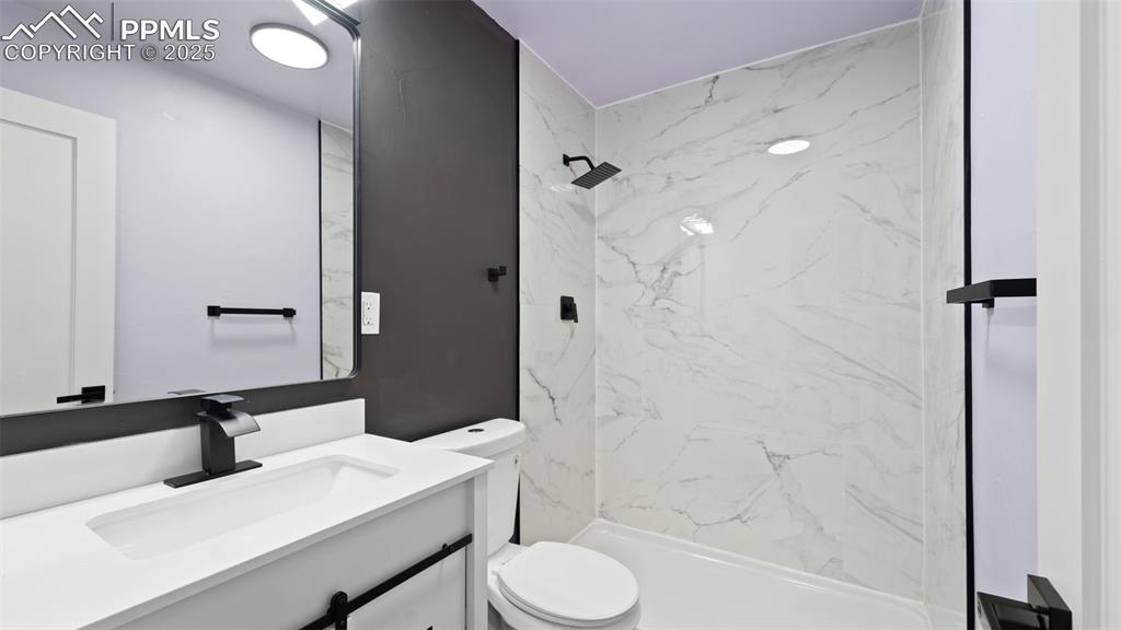 Image 15 of 28: Bathroom with vanity and a marble finish shower