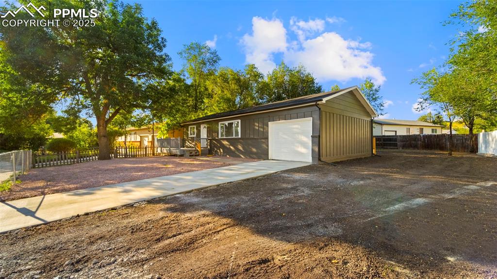 Image 3 of 28: View of front facade featuring concrete driveway, board and batten siding, 