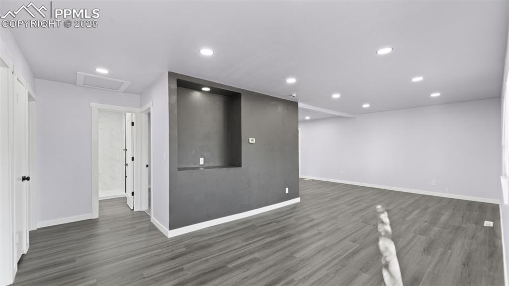 Image 5 of 28: Unfurnished living room featuring attic access, dark wood-style flooring, a