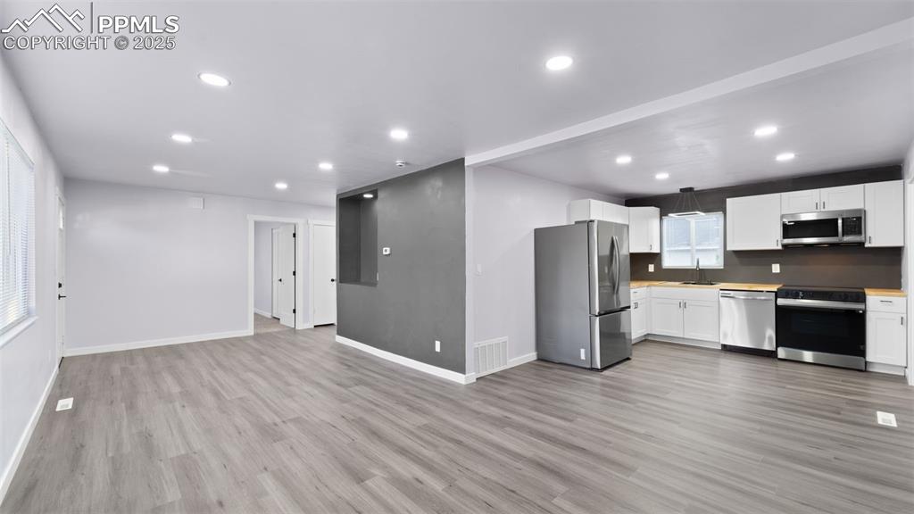 Image 8 of 28: Kitchen with appliances with stainless steel finishes, white cabinets, ligh