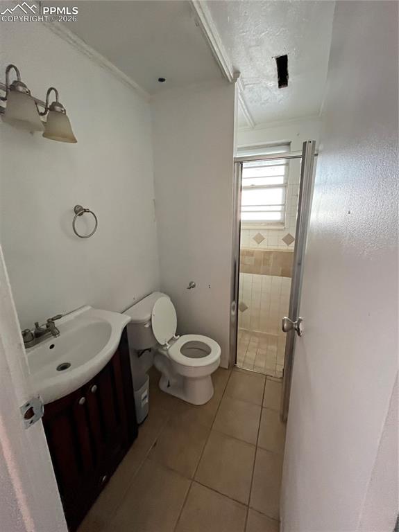 Image 10 of 13: Full bathroom with vanity, a shower stall, light tile patterned floors, and