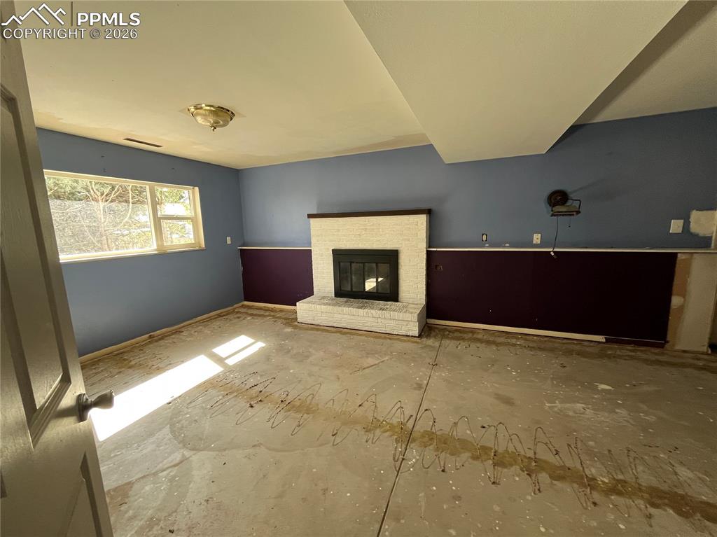 Image 9 of 13: Unfurnished living room with a fireplace and baseboards