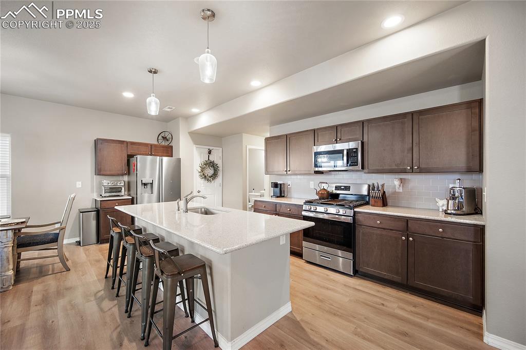 Image 8 of 36: Huge island, gas range, SS applainces, darker wood cabinetry, kitchen pantr