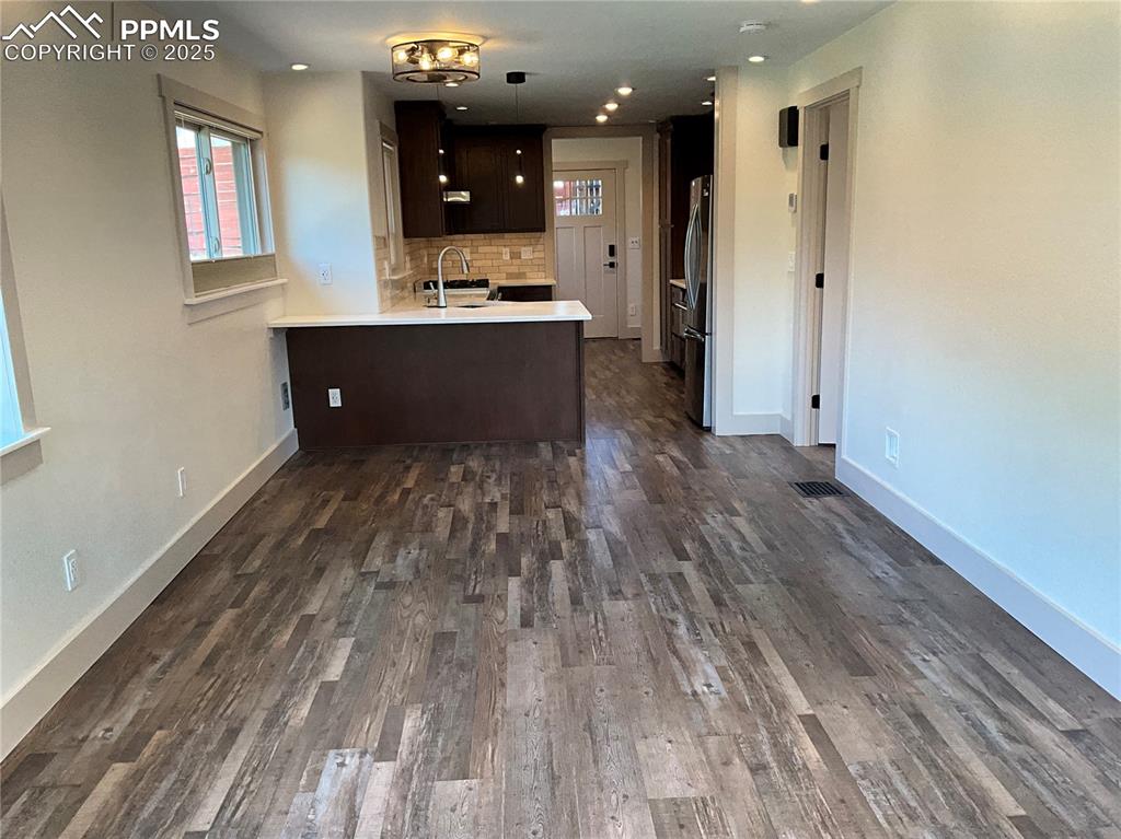 Image 14 of 50: Kitchen with dark brown cabinetry, light Quartz countertops, tasteful backs