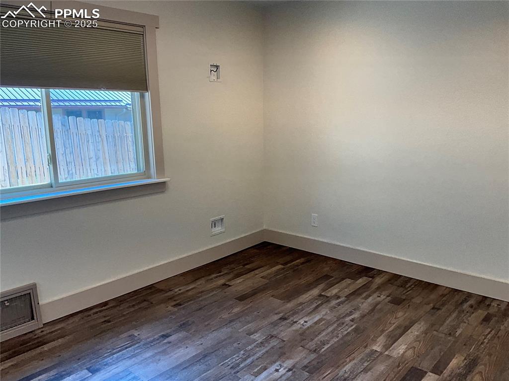Image 17 of 50: Empty room with dark wood-style flooring