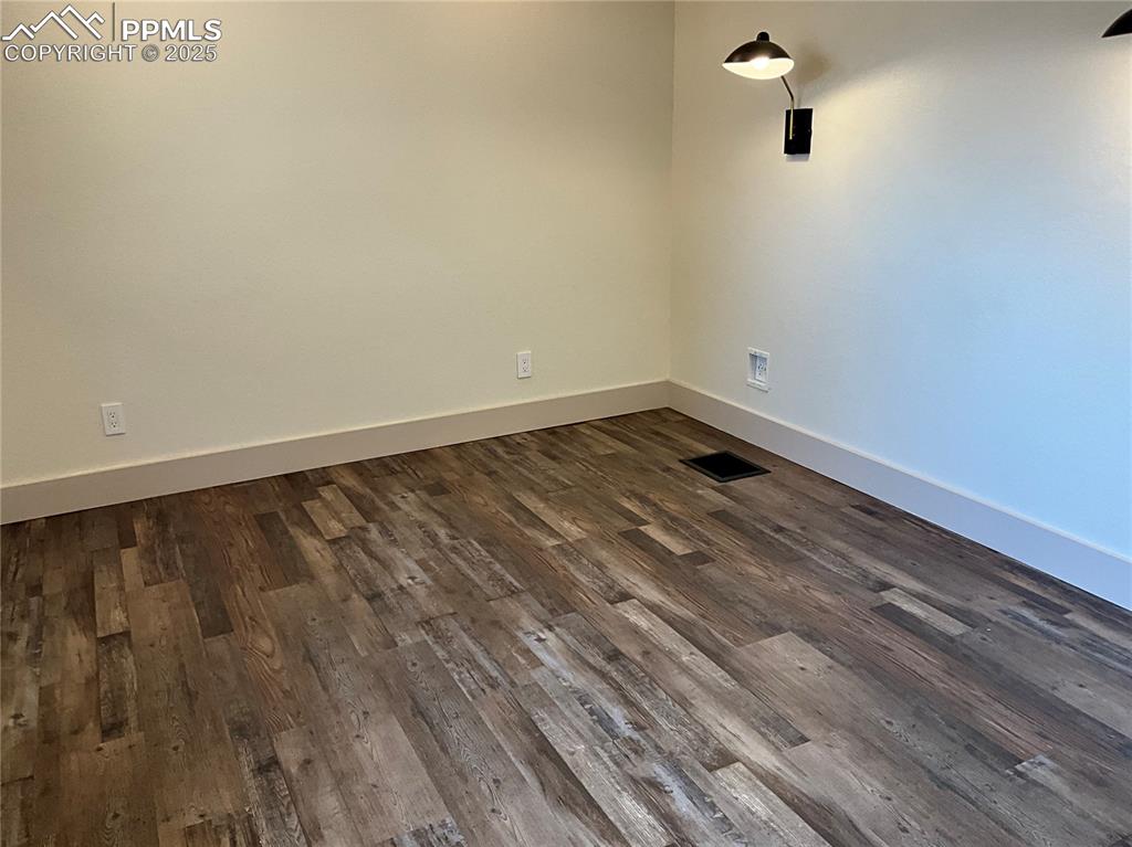 Image 19 of 50: Empty room featuring baseboards and dark wood-style floors