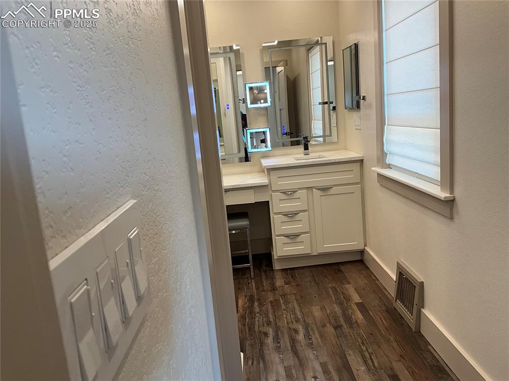 Image 20 of 50: Half bath with a textured wall, vanity, and dark wood-style floors