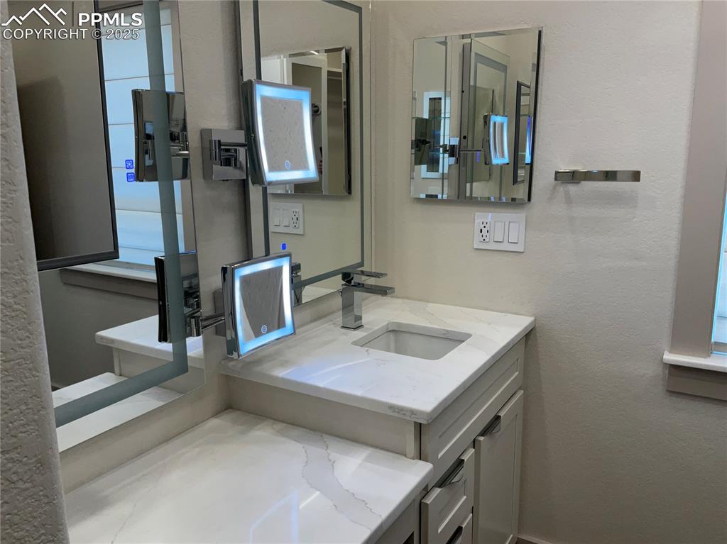 Image 27 of 50: Bathroom featuring a textured wall, vanity, and plenty of natural light