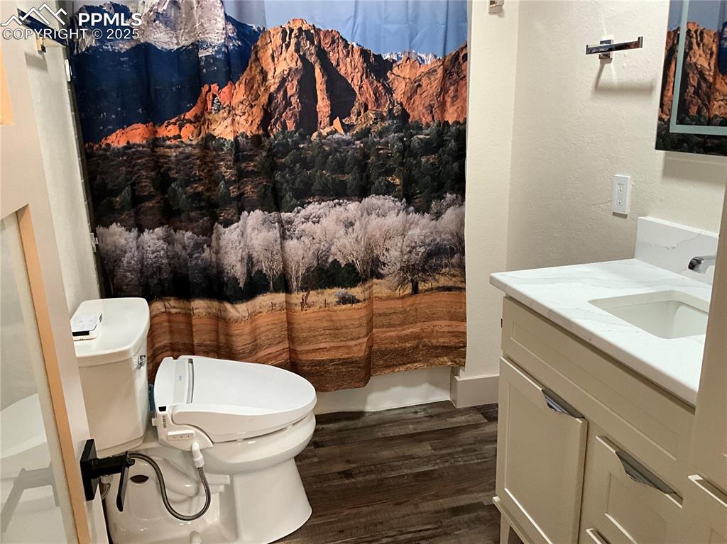 Image 30 of 50: Full bathroom with vanity, dark wood-style floors, a textured wall, and cur