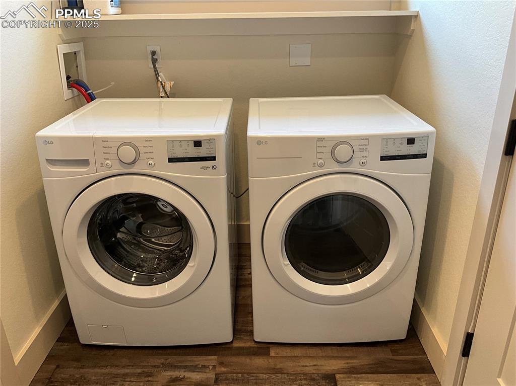 Image 34 of 50: Laundry area featuring washing machine and dryer, dark wood-type flooring,