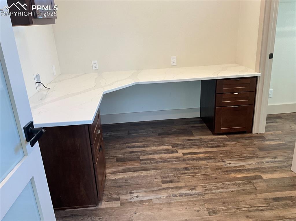 Image 35 of 50: Unfurnished office with built in desk and dark wood-style flooring