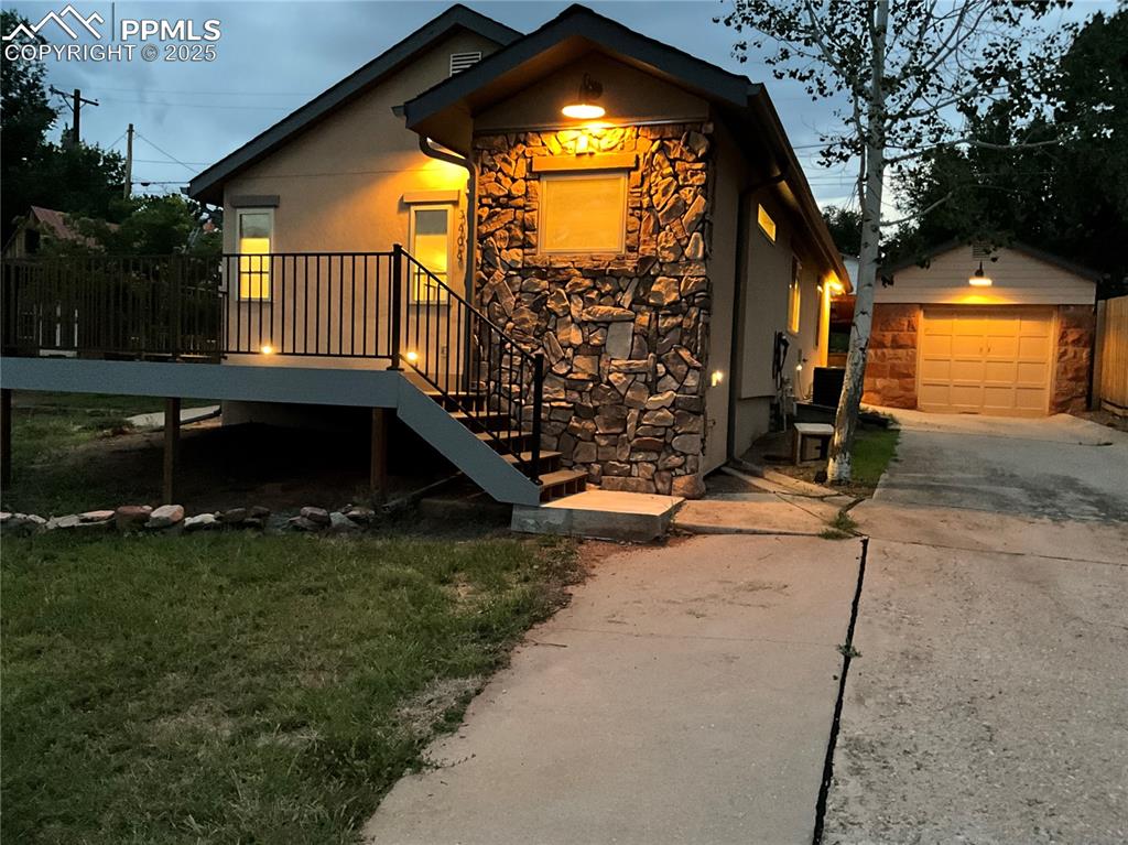 Image 48 of 50: View of side of property featuring stone siding, concrete driveway, an outb