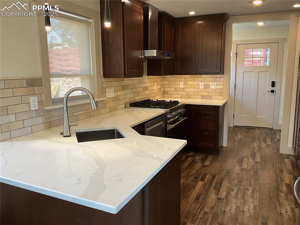 Image 7 of 50: Kitchen featuring Cherry Charcoal cabinetry, wall chimney range hood, deco