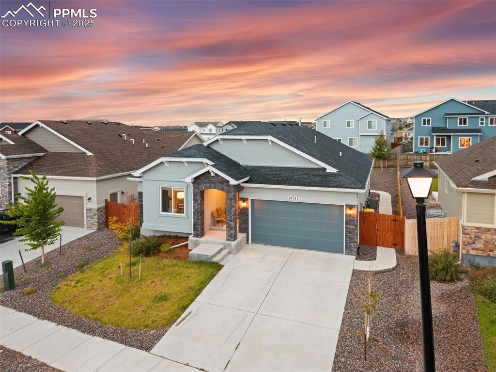 Caption: Craftsman inspired home featuring stone siding, concrete driveway, a garage, and roof with shingles