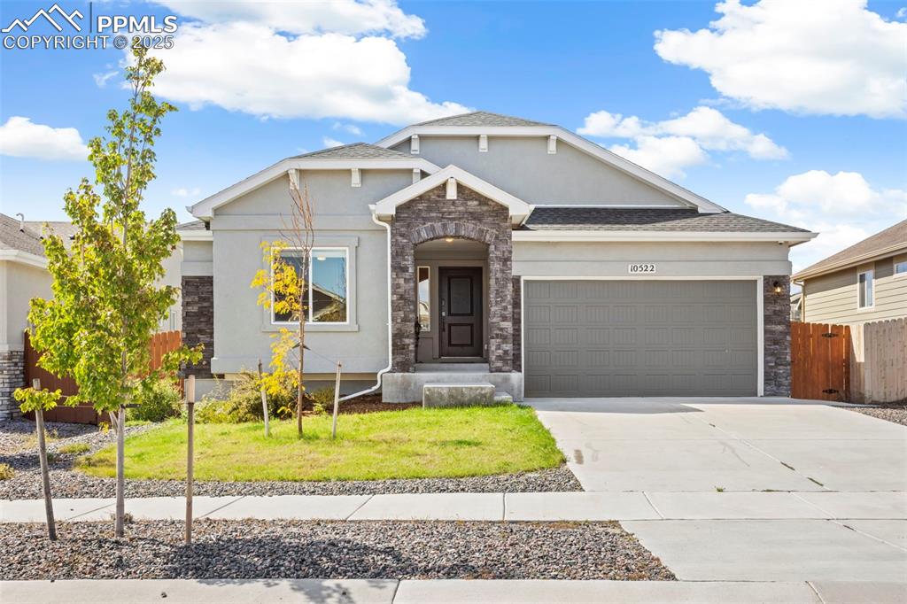 Image 10 of 41: Craftsman house with stone siding, driveway, a garage, and stucco siding