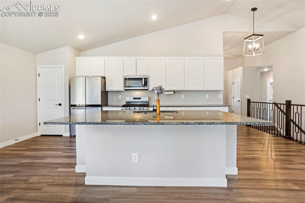 Image 18 of 41: Kitchen featuring white cabinetry, dark stone counters, appliances with sta