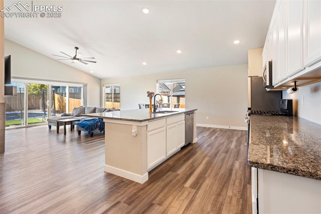Image 19 of 41: Kitchen featuring white cabinetry, dark stone counters, open floor plan, re