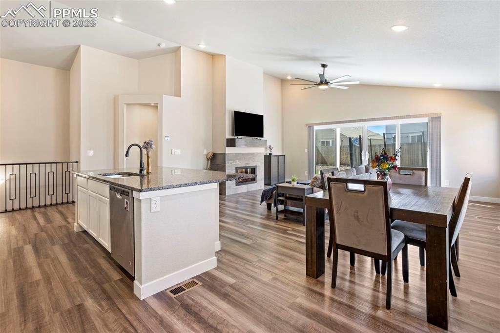 Image 20 of 41: Kitchen featuring dark stone countertops, a kitchen island with sink, open