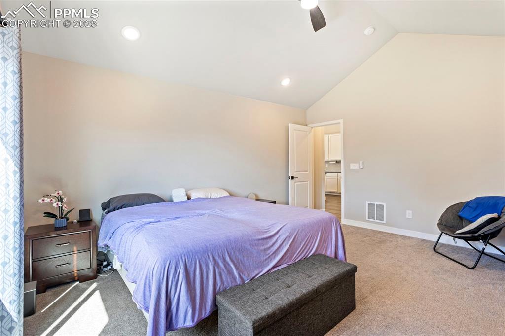 Image 22 of 41: Carpeted bedroom with a ceiling fan, high vaulted ceiling, and recessed lig