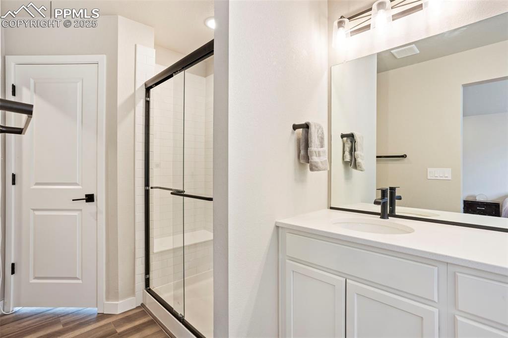 Image 24 of 41: Bathroom with a shower stall, vanity, dark wood-style flooring, and ensuite