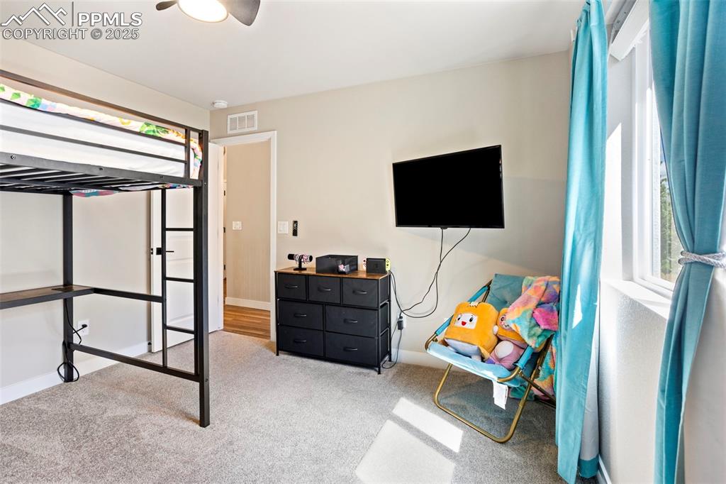 Image 27 of 41: Bedroom with light carpet, multiple windows, and a ceiling fan