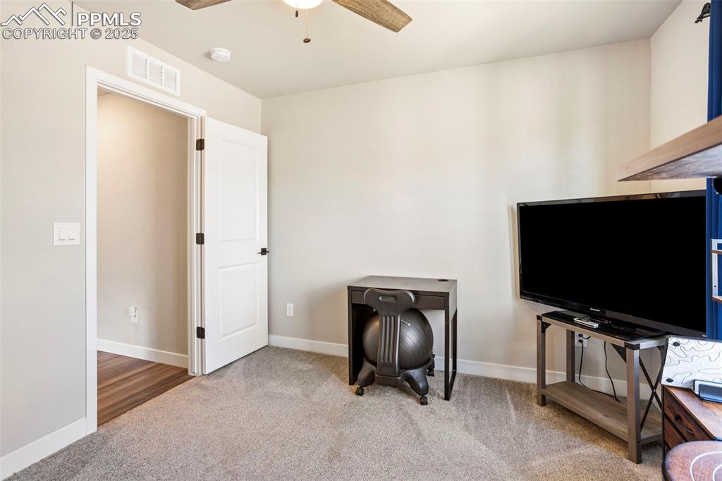 Image 30 of 41: Living area with light colored carpet and ceiling fan