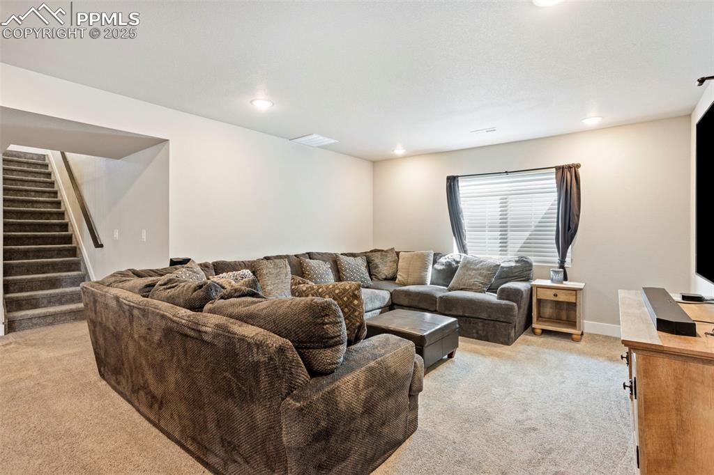 Image 33 of 41: Living area featuring light carpet, stairway, and recessed lighting