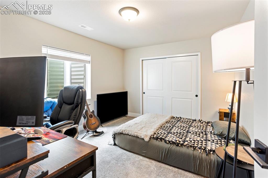 Image 37 of 41: Bedroom featuring a desk, light carpet, and a closet