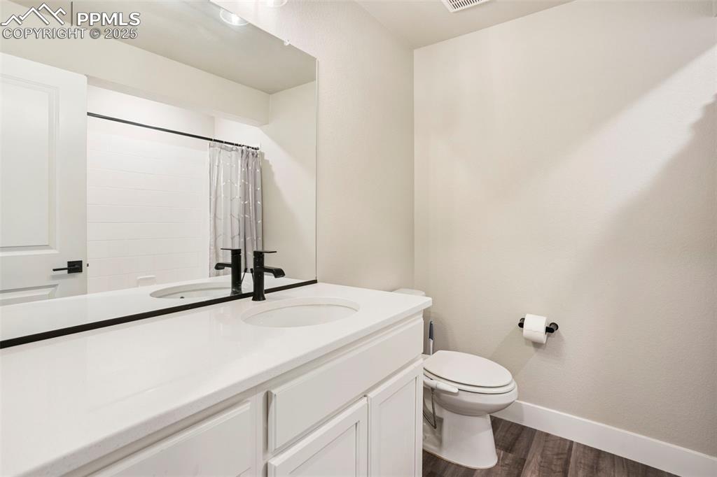 Image 38 of 41: Bathroom with dark wood-type flooring, vanity, and a shower with shower cur