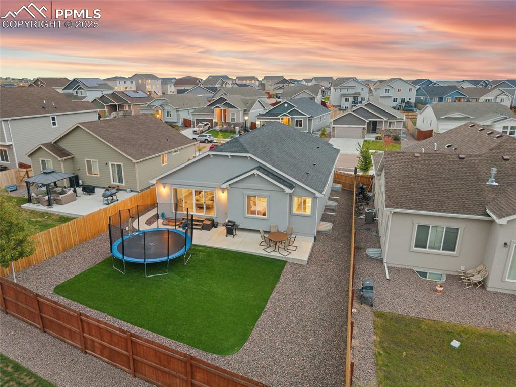 Image 6 of 41: Back of house featuring a patio area, a trampoline, a fenced backyard, and