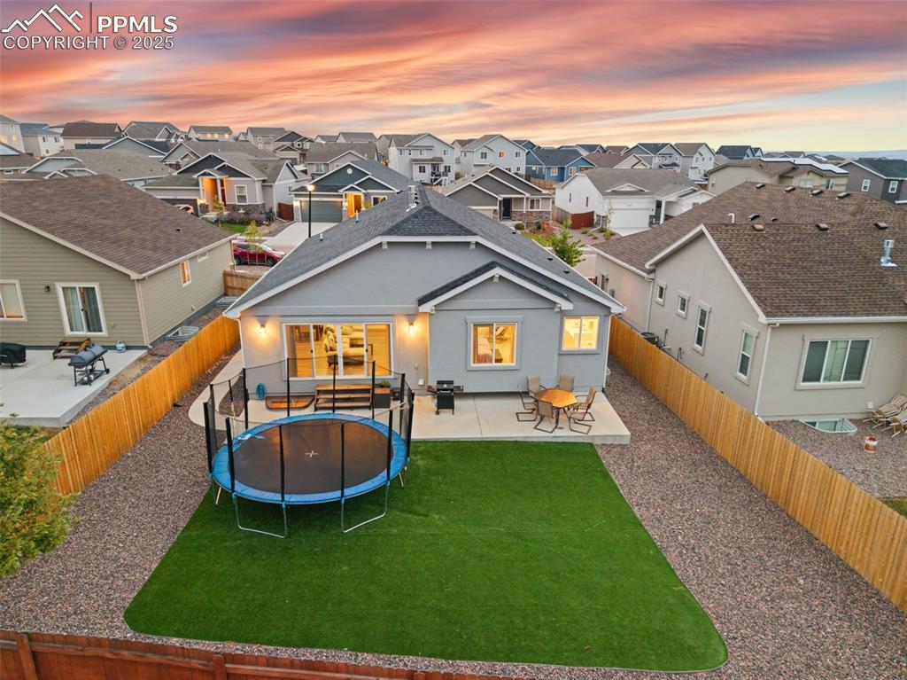 Image 7 of 41: Rear view of property featuring a patio, stucco siding, a trampoline, a fen